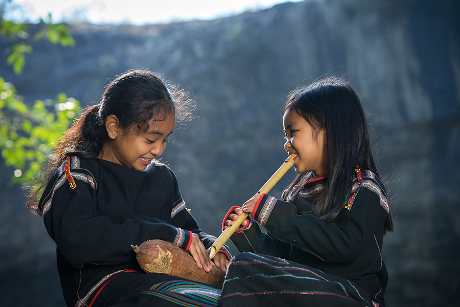Two-Ede-ethnic-minority-little-girls-learning-to-play-the-flute-in-forest-in-Man-Nguyen-Private-Vietnam-Tour-Packages